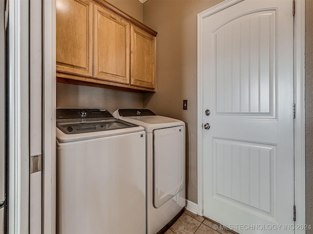 clothes washing area featuring washing machine and clothes dryer, light tile patterned floors, and cabinets