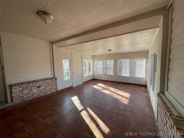 unfurnished sunroom featuring beam ceiling