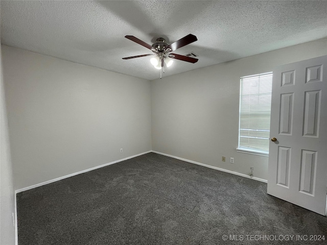 unfurnished room with a textured ceiling, dark carpet, and ceiling fan