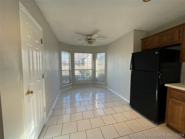 kitchen featuring ceiling fan, black refrigerator, and light tile patterned flooring