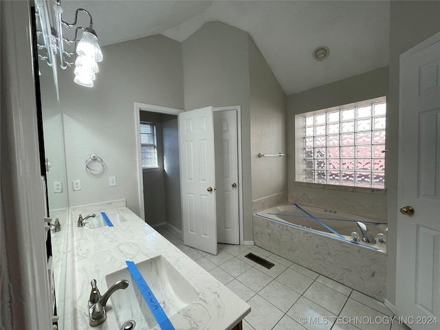 bathroom with tile patterned floors, vanity, a wealth of natural light, and tiled bath