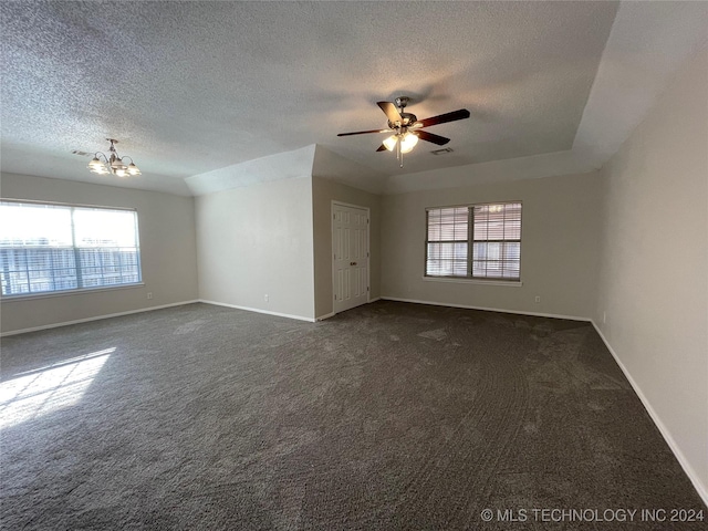 spare room with dark colored carpet, a textured ceiling, and a wealth of natural light