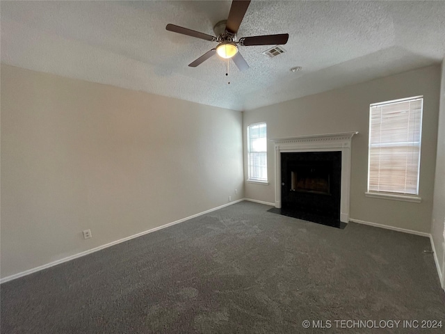 unfurnished living room with ceiling fan, dark carpet, and a textured ceiling