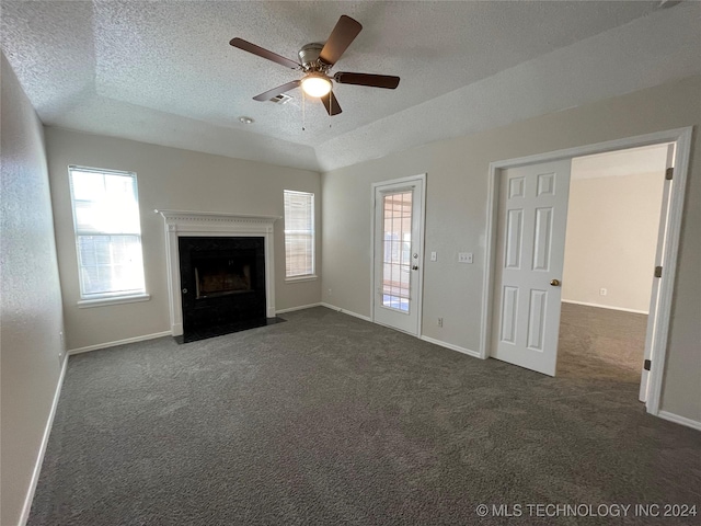 unfurnished living room with ceiling fan, dark carpet, and a textured ceiling