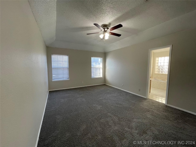 spare room with dark colored carpet, ceiling fan, and a textured ceiling