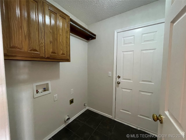 laundry room featuring electric dryer hookup, cabinets, washer hookup, dark tile patterned floors, and a textured ceiling