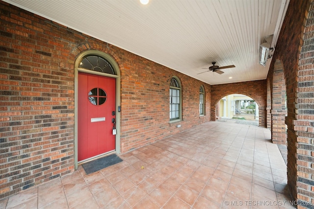 view of exterior entry featuring ceiling fan and a porch