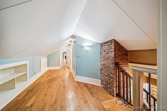 bonus room featuring vaulted ceiling, built in features, and light hardwood / wood-style floors