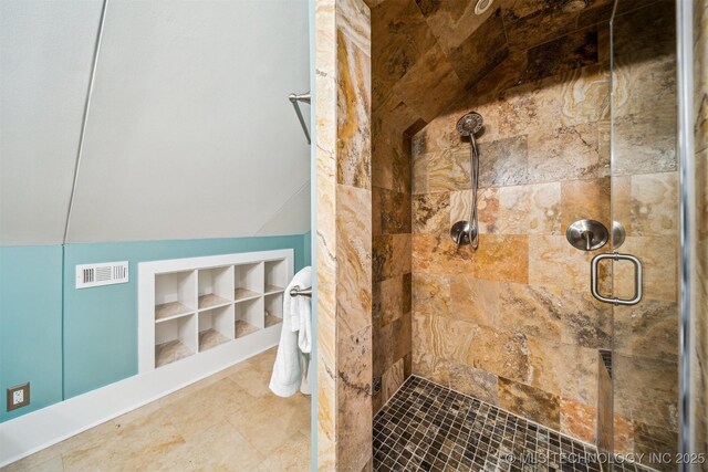 bathroom with built in shelves, lofted ceiling, and walk in shower