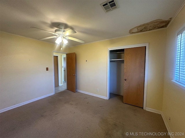 unfurnished bedroom with ceiling fan, light colored carpet, ornamental molding, and a closet