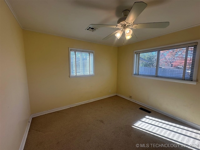 empty room featuring ceiling fan, carpet floors, and a healthy amount of sunlight