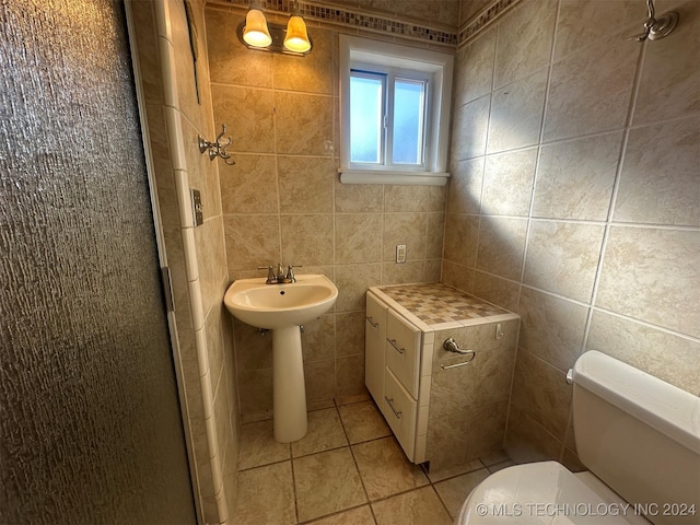 bathroom with tile patterned flooring, sink, toilet, and tile walls