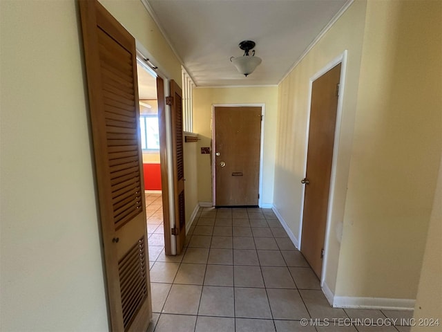 hallway with ornamental molding and light tile patterned flooring