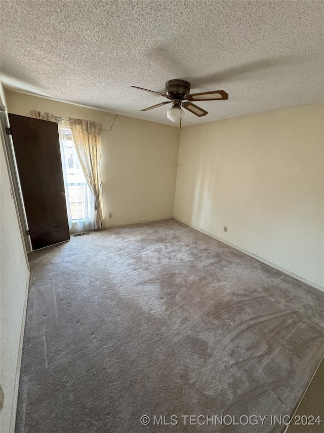 unfurnished room with a textured ceiling, carpet floors, and ceiling fan