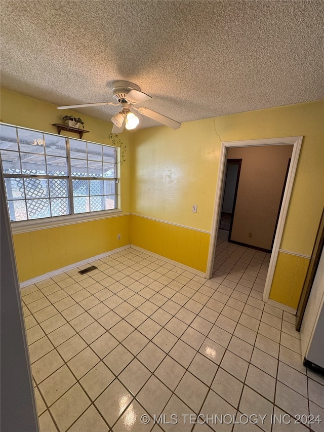 tiled empty room with a textured ceiling and ceiling fan