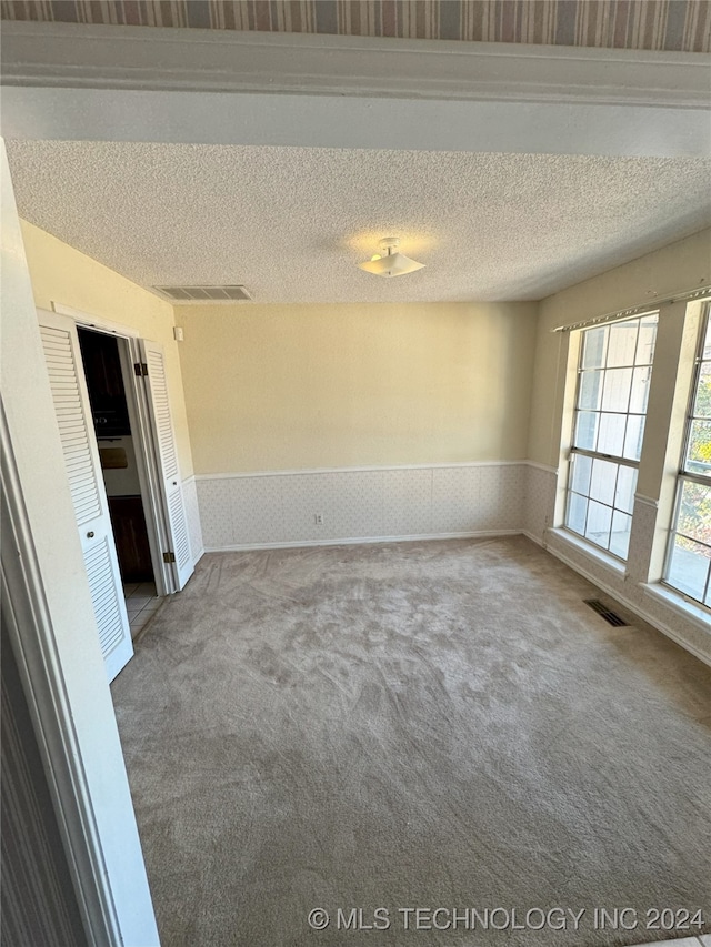 unfurnished room featuring carpet and a textured ceiling