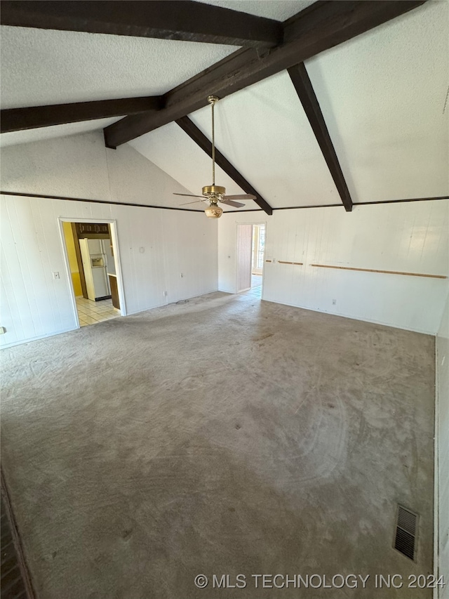 unfurnished living room featuring carpet flooring, vaulted ceiling with beams, ceiling fan, and a textured ceiling