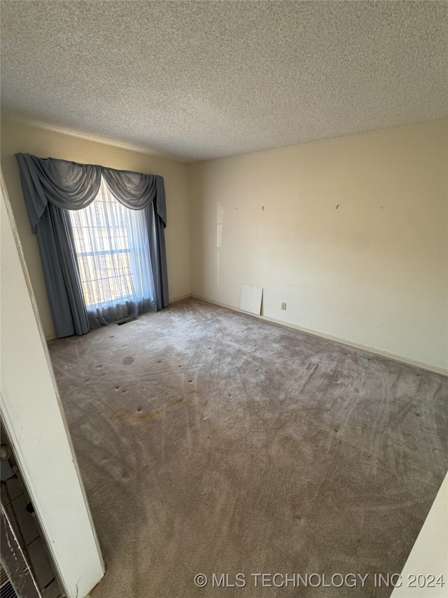 carpeted empty room with a textured ceiling