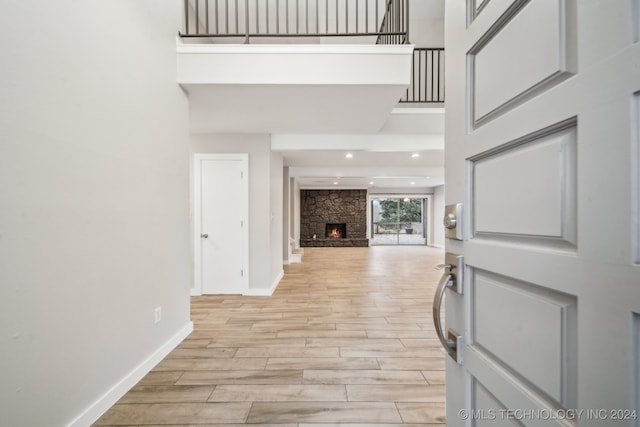 foyer entrance featuring a fireplace, a high ceiling, and light hardwood / wood-style flooring