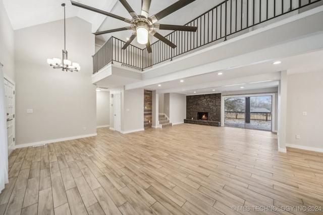 unfurnished living room featuring ceiling fan with notable chandelier, a towering ceiling, and a fireplace