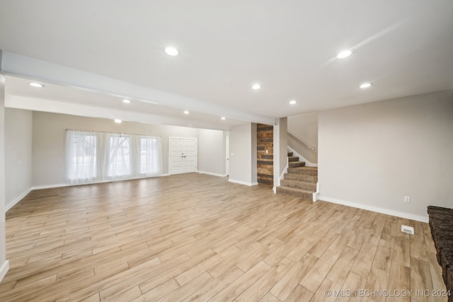 unfurnished living room with recessed lighting, baseboards, light wood-style floors, and stairs