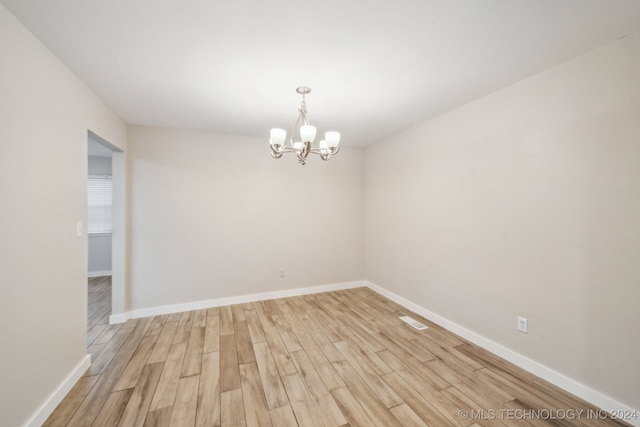 unfurnished room featuring a chandelier and light hardwood / wood-style floors