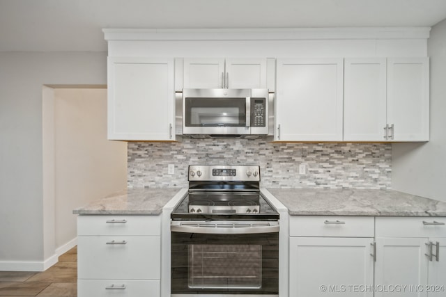 kitchen featuring backsplash, white cabinets, light wood-type flooring, light stone countertops, and appliances with stainless steel finishes