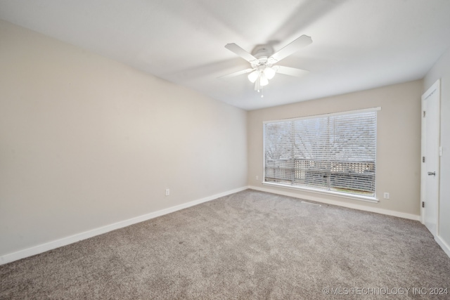 carpeted spare room featuring a ceiling fan and baseboards