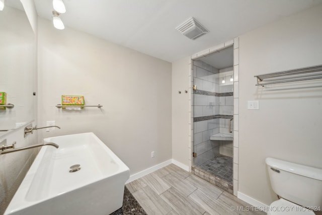 bathroom with sink, an enclosed shower, and toilet