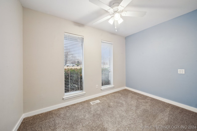 carpeted spare room with visible vents, baseboards, and ceiling fan