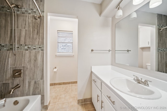 full bathroom featuring tile patterned flooring, vanity, tiled shower / bath combo, and toilet