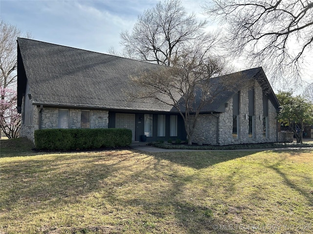 view of front of home with stone siding, a shingled roof, and a front lawn