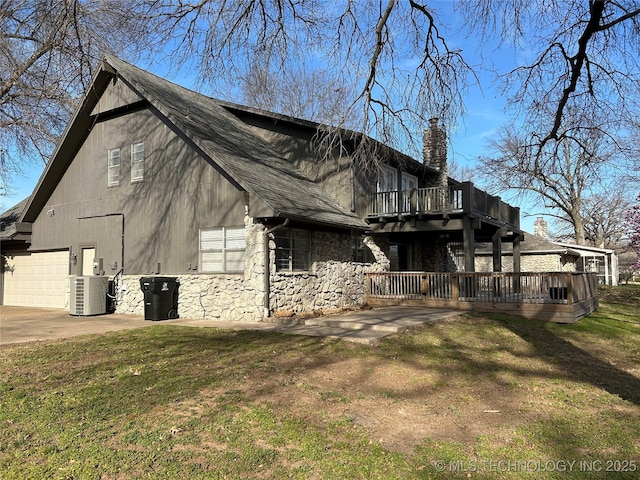 view of side of home featuring cooling unit, a yard, a garage, stone siding, and a deck