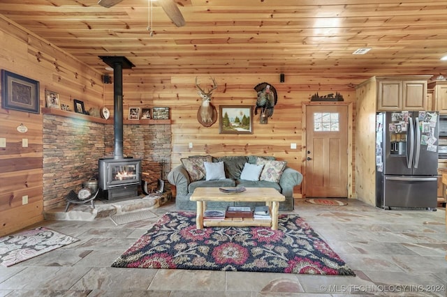 living room with wooden walls, a wood stove, and wood ceiling