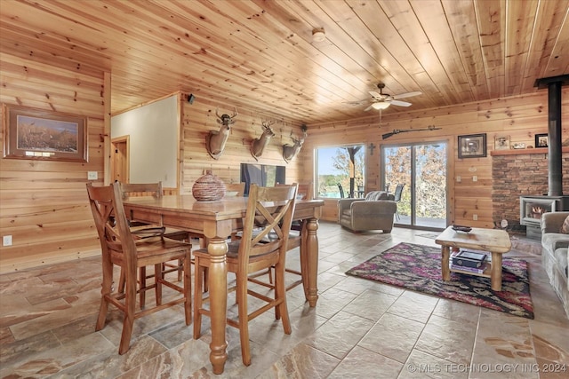 dining space with wood walls, a wood stove, and wood ceiling