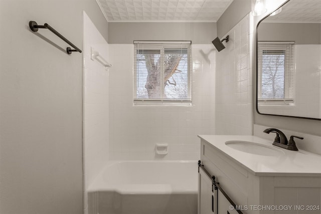 bathroom featuring tiled shower / bath, a wealth of natural light, vanity, and ornamental molding