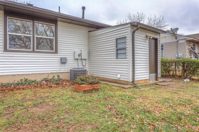 view of side of home with a lawn and cooling unit