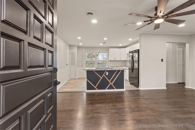 kitchen featuring white cabinetry, a center island, dark wood-type flooring, light stone counters, and backsplash