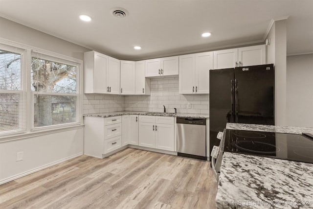 kitchen with black refrigerator, white cabinets, stainless steel dishwasher, and stove