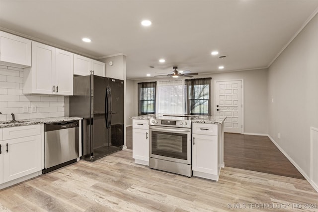 kitchen with light stone countertops, white cabinetry, tasteful backsplash, appliances with stainless steel finishes, and light wood-type flooring