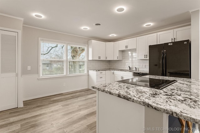 kitchen with light stone countertops, white cabinetry, and black appliances