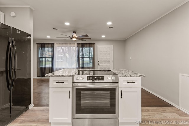 kitchen featuring stainless steel range with electric stovetop, white cabinets, light stone counters, and black fridge