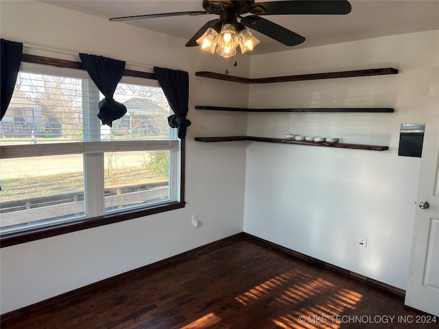 empty room with plenty of natural light, ceiling fan, and dark hardwood / wood-style flooring