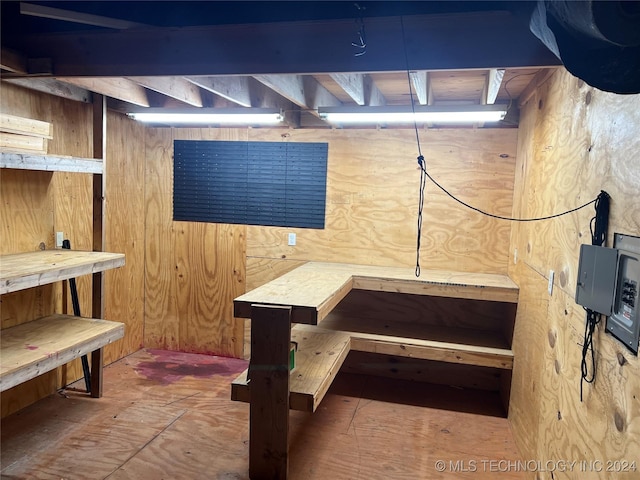 basement with a workshop area and wooden walls