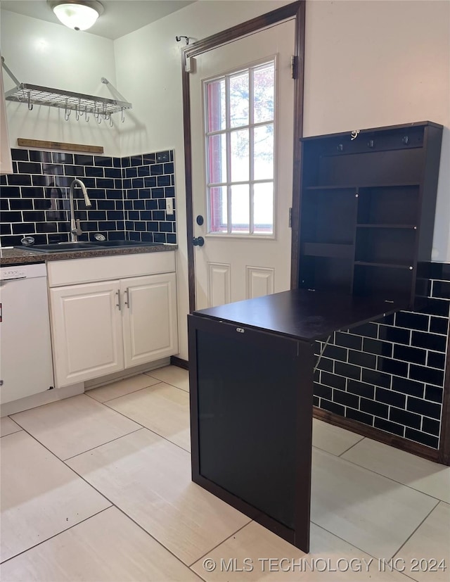 kitchen with sink, light tile patterned floors, backsplash, white dishwasher, and white cabinets