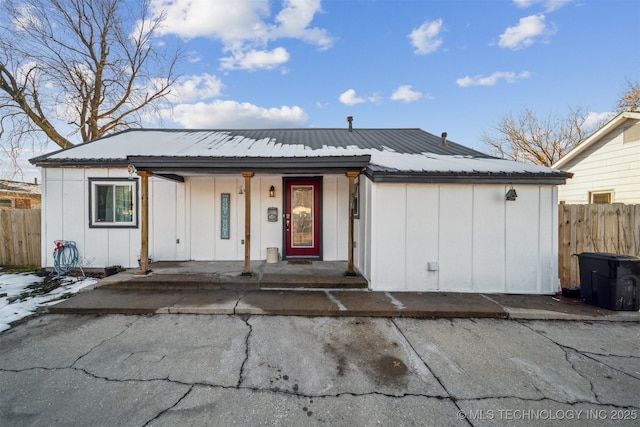 view of front facade featuring board and batten siding, metal roof, fence, and a porch