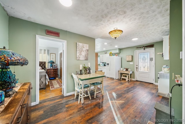 dining area with a textured ceiling and dark hardwood / wood-style flooring