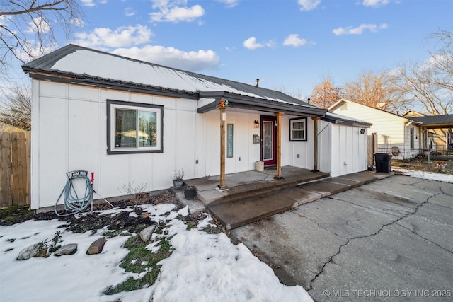 view of front of property featuring metal roof, a porch, board and batten siding, and fence