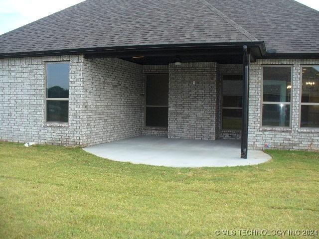 rear view of house featuring a lawn and a patio