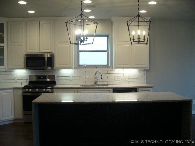 kitchen with white cabinets, appliances with stainless steel finishes, a center island, and sink